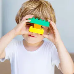 5 letnie dziecko bawi się klockami, tworząc z nich okulary.