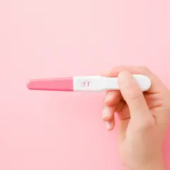 Dłoń trzyma test ciążowy z dwoma różowymi kreskami. To może być początek nowej drogi, nawet jeśli ciąża w młodym wieku niesie wyzwania.