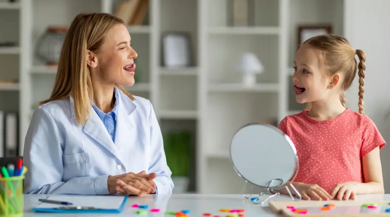 Logopeda ćwiczy z dzieckiem ruchy języka, co może pomóc w diagnozie chorób mylonych z autyzmem.