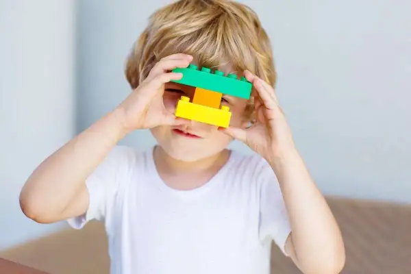 5 letnie dziecko bawi się klockami, tworząc z nich okulary.